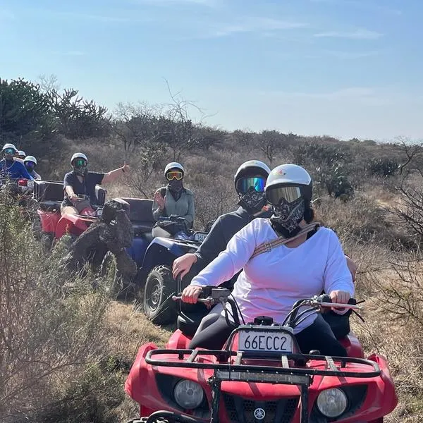 Guey Tours Exploring Agua Espinoza on Exciting ATV Tours A group of riders on red ATVs, led by Guey Tours, on a dusty trail through the arid landscape of Agua Espinosa.